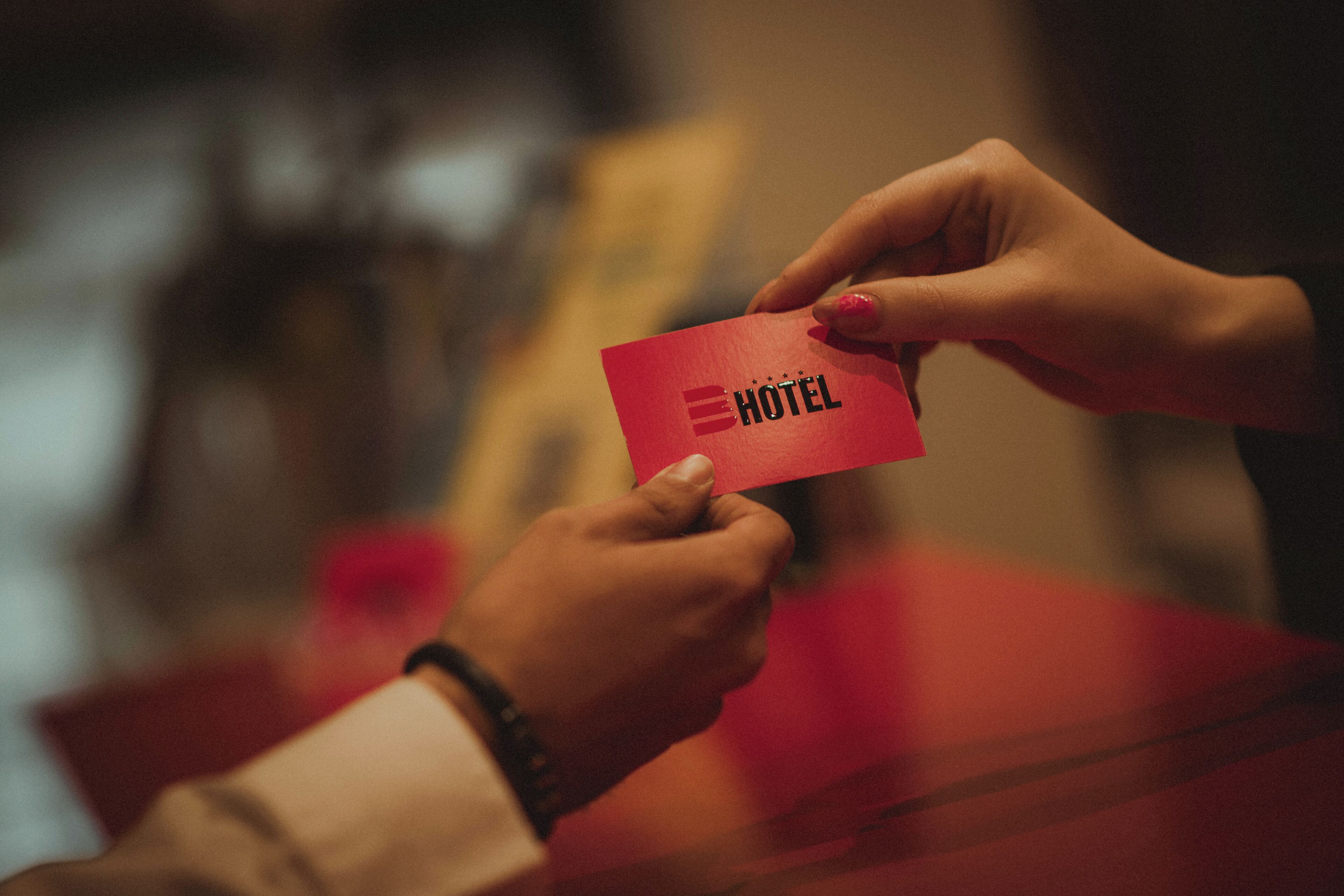 Eine Hand hält eine rote Karte mit dem Wort 'HOTEL'.
