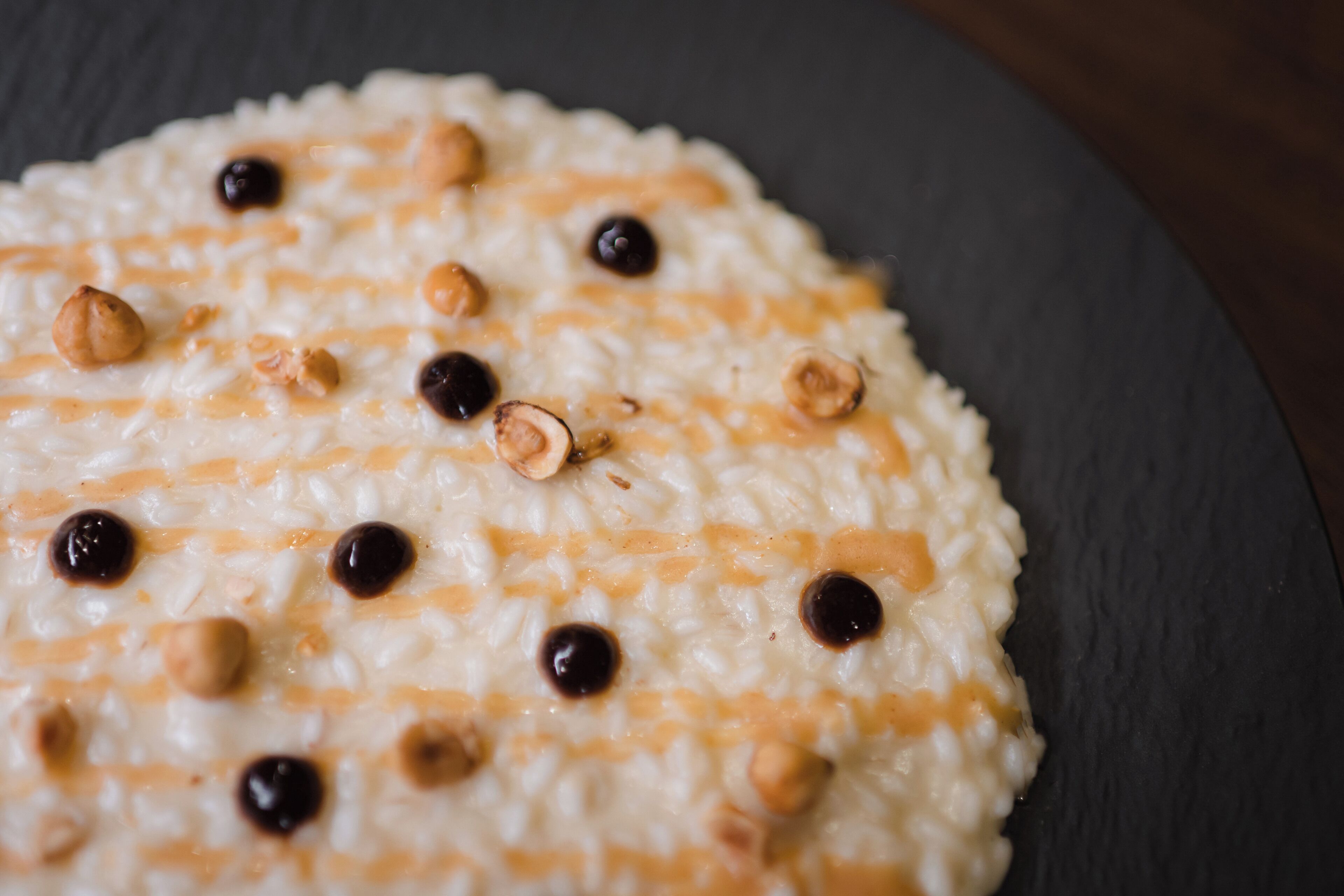 Eine Nahaufnahme eines Desserts mit cremiger Textur, bestreut mit Haselnüssen und Schokoladenstückchen.
