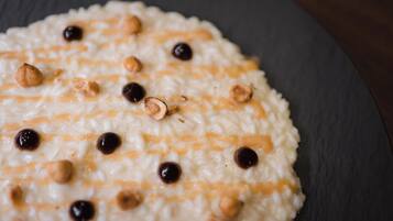 Eine Nahaufnahme eines Desserts mit cremiger Textur, bestreut mit Haselnüssen und Schokoladenstückchen.