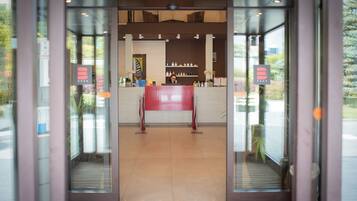 Zona de recepción con puerta de cristal, mostrador de recepción y exhibición de artículos de aseo.