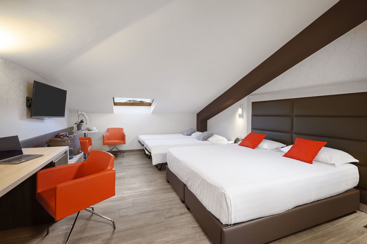 Una habitación de hotel con escritorio, dos camas y televisión.
