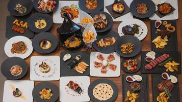 Una variedad de platos sobre una mesa de madera, incluyendo bistec, papas fritas y ensaladas.