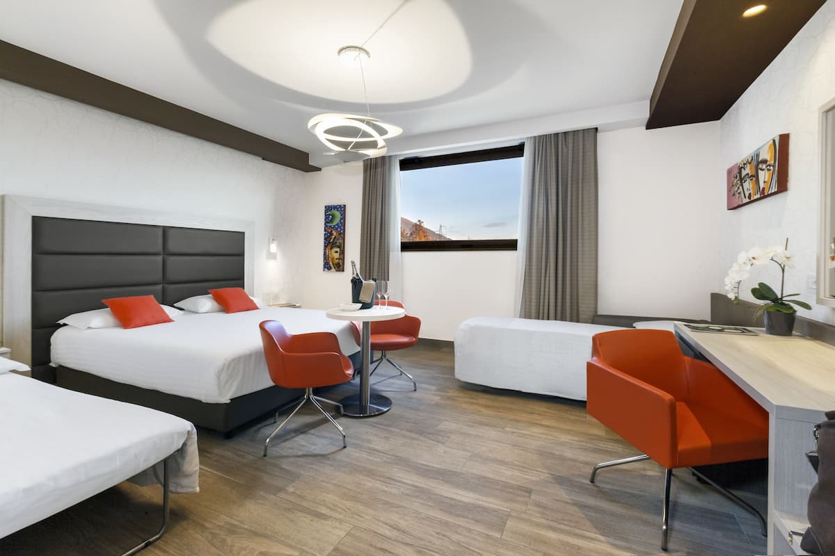 Una habitación de hotel con dos camas, un escritorio, una silla y una pequeña mesa.
