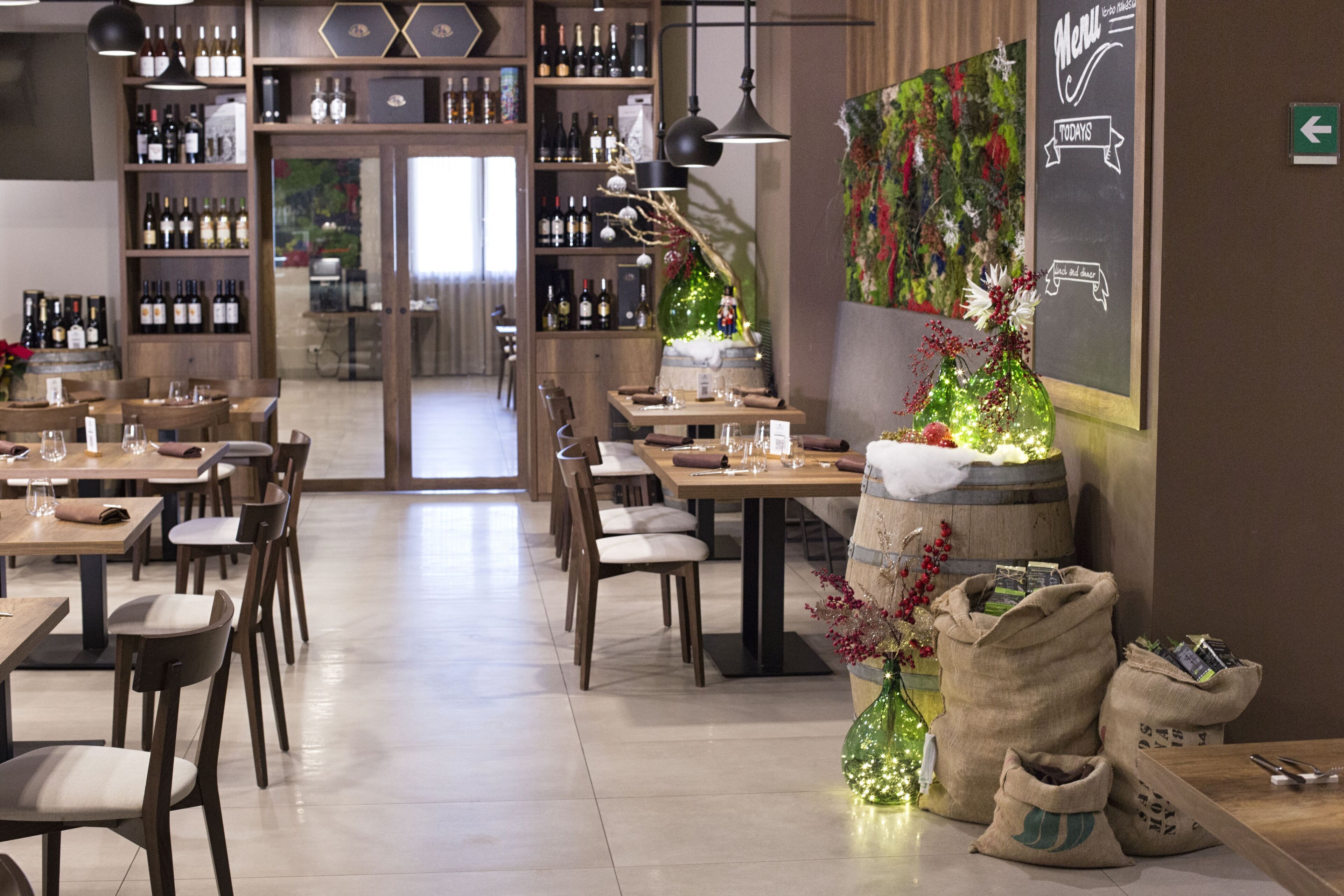 A restaurant with wooden tables and chairs, a wine rack, and a chalkboard menu.