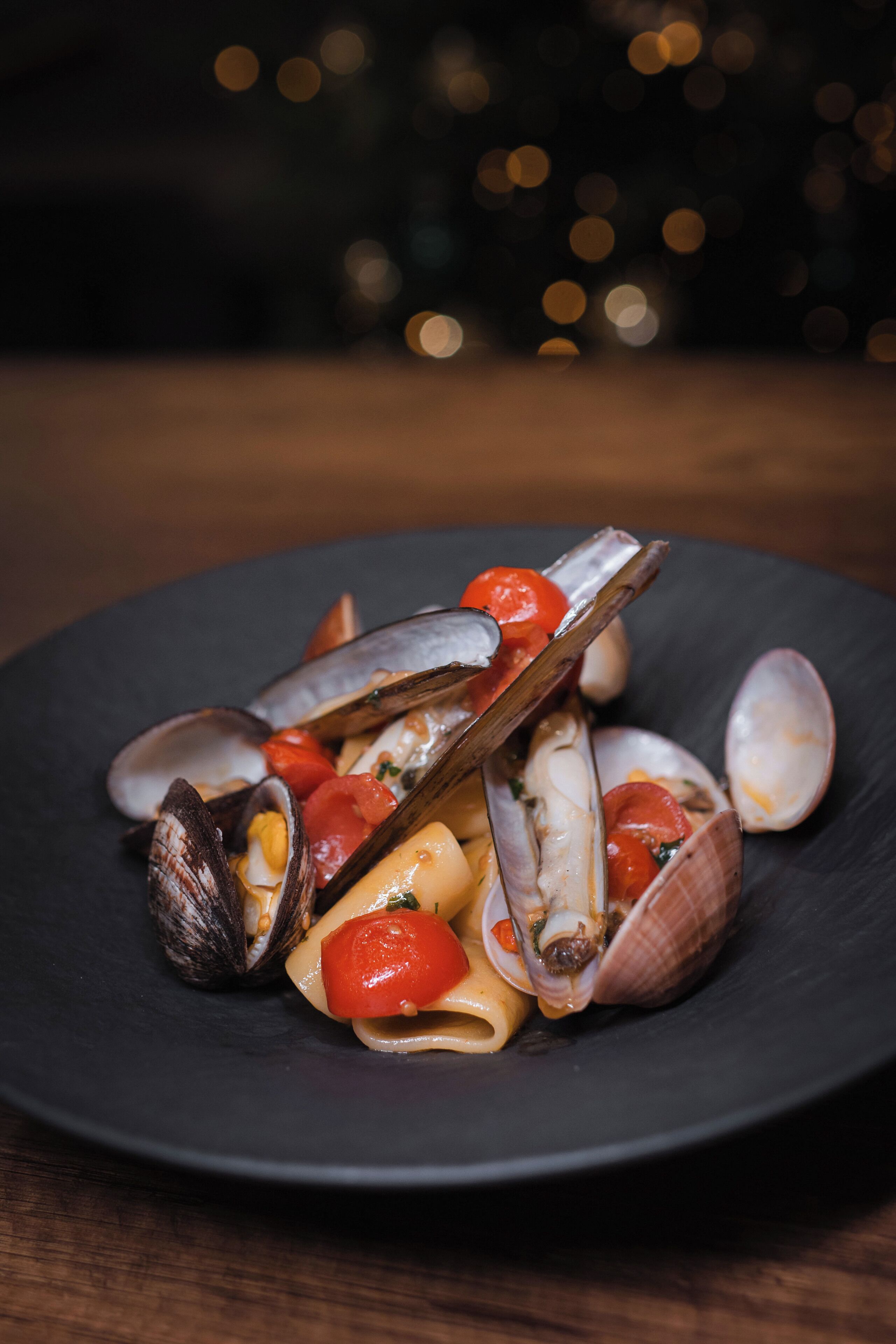 Un plato de almejas con tomates y hierbas aromáticas.