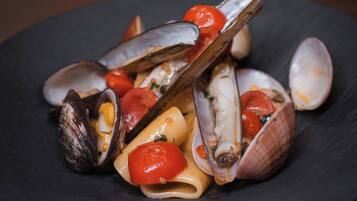 Un plato de almejas con tomates y hierbas aromáticas.