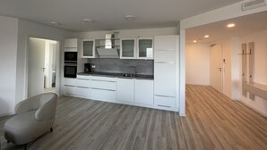 Una cucina moderna con mobili bianchi, forno integrato e piano di lavoro grigio.