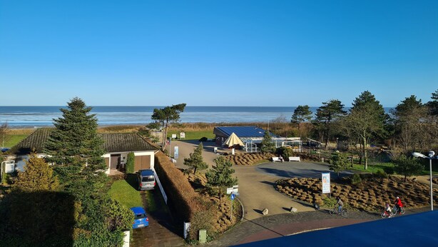 Una zona residenziale sul lungomare, con vista libera sul mare, un’area di parcheggio e un piccolo parco con panchine e un’area giochi.