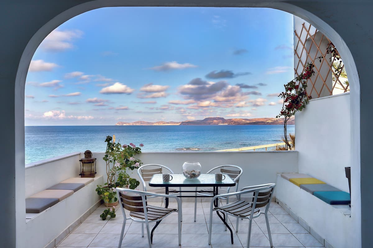 Un balcón con una mesa y sillas, con vista al mar.