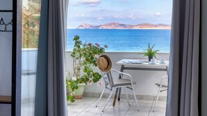 A room with a bed, a balcony with a table and chairs, and a view of the sea. - Blue Comfort Apartments Sitia (Sitia)