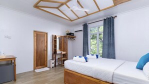 Un dormitorio con cama de madera, un escritorio, una silla, un armario y una ventana con cortinas.