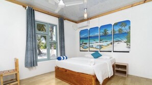 Un dormitorio con cama de madera, ventana con cortinas, ventilador de techo y un mural temático de playa.