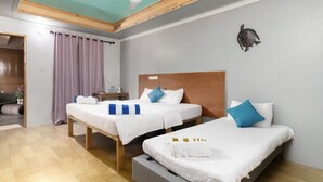 Habitación con dos camas, ventilador de techo y decoración de tortuga en la pared.