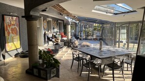 A spacious indoor area with a large table and chairs, a ceiling with skylights, and a view of the outside. - LARGE ATYPICAL VILLA WITH PRIVATE POOL IN A QUIET LOCATION (La Farlède)