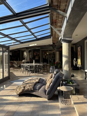 Ein offener Wohnbereich mit Glasdecke, einer Steinsäule und einem Sofa mit Felldecke.