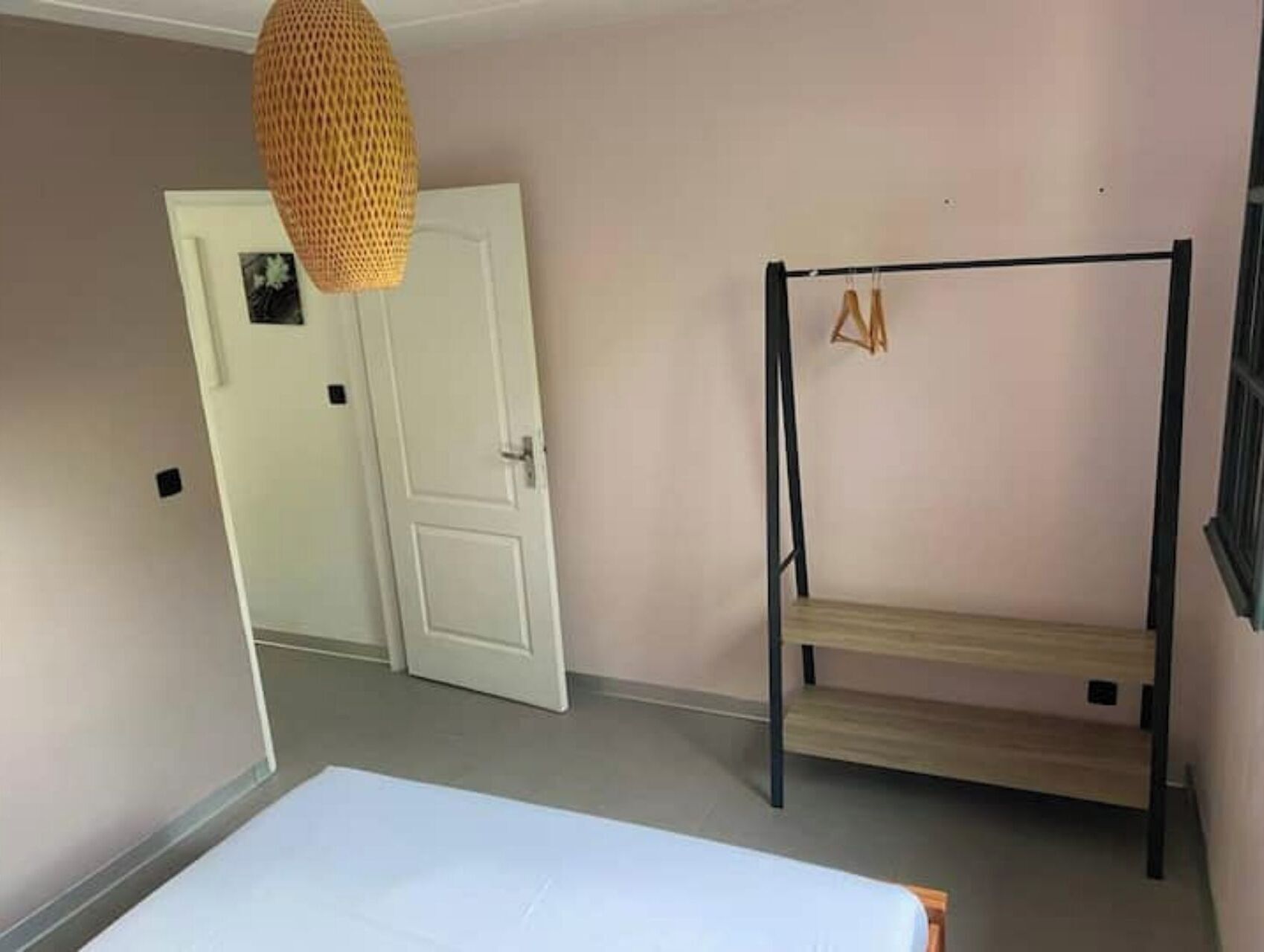 A room with a bunk bed, a door, and a hanging light fixture.