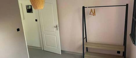 A room with a bunk bed, a door, and a hanging light fixture.