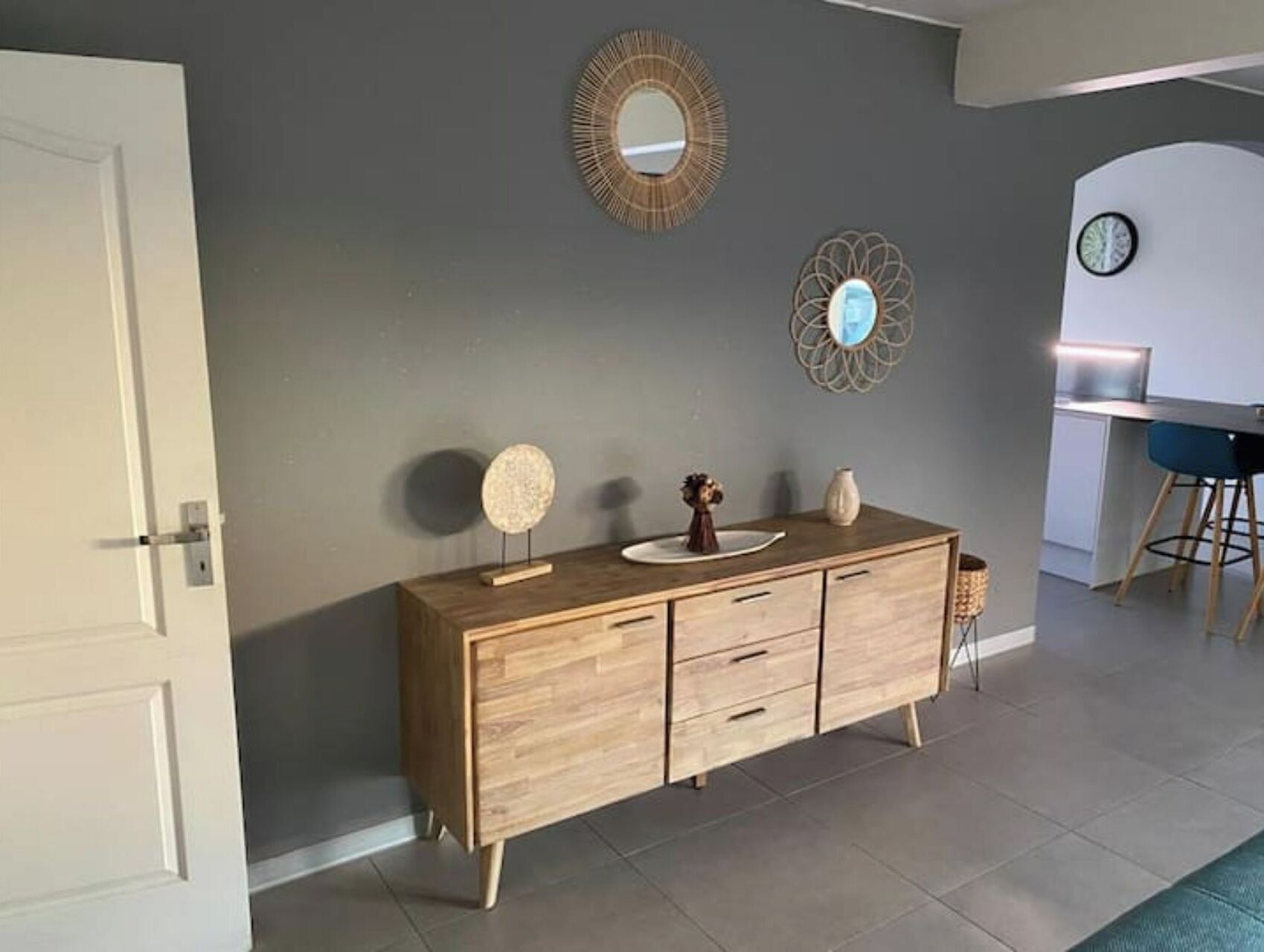 Une cuisine moderne avec des meubles en bois, un miroir rond et un élément décoratif mural.