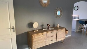 A modern kitchen with a wooden cabinet, a round mirror, and a decorative wall piece. - Villa with swimming pool in the center of st louis river (Saint-Louis)