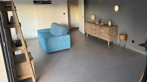 A spacious living room with a light blue sofa, a wooden cabinet, and a painting on the wall. - Villa with swimming pool in the center of st louis river (Saint-Louis)