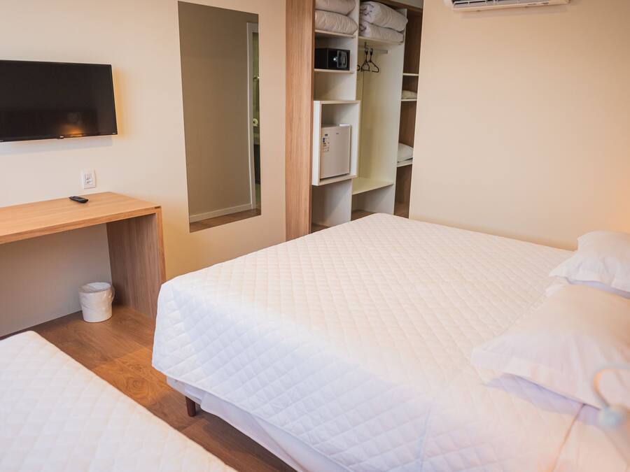 Quarto com cama, escrivaninha e televisão.