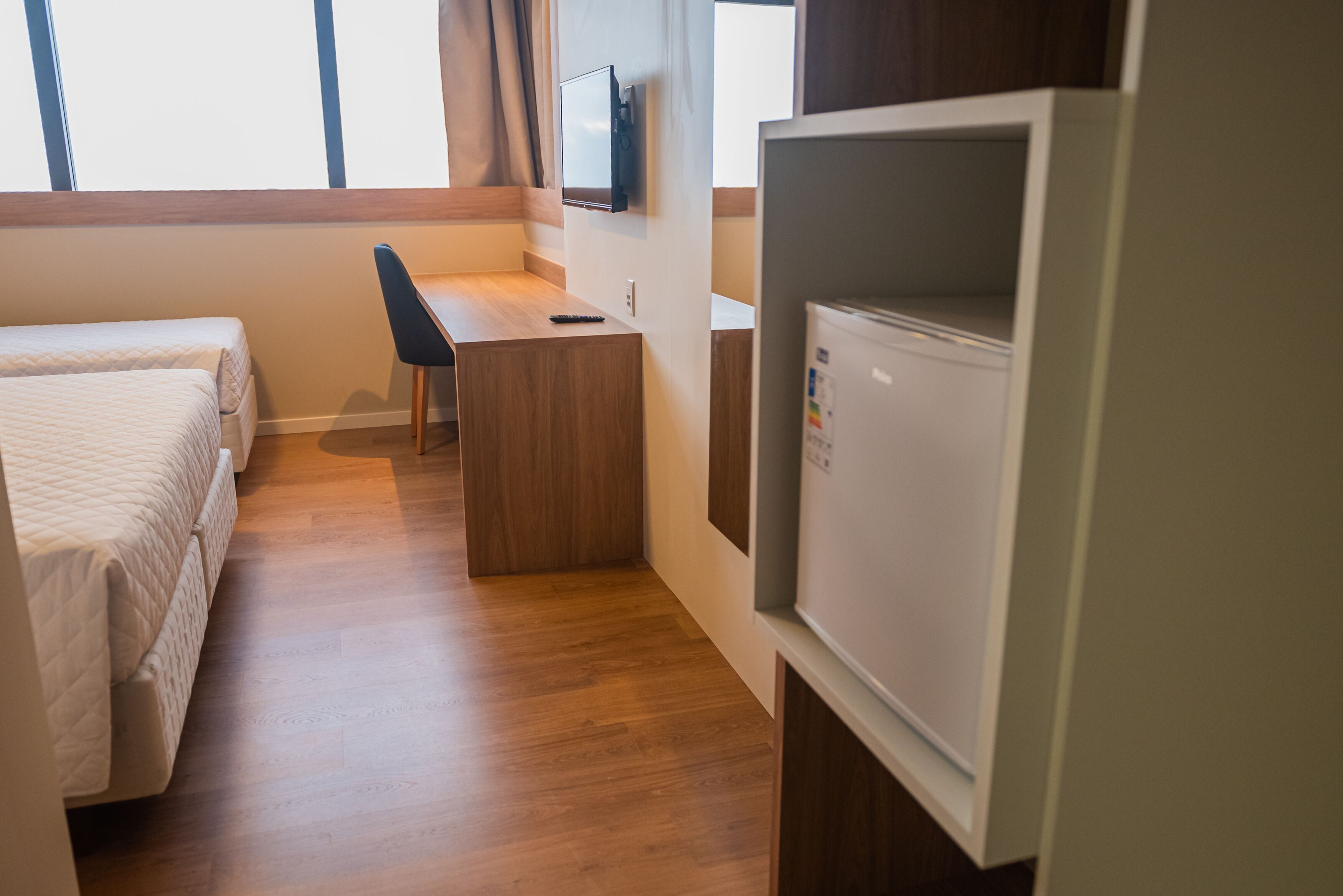 A hotel room with a bed, a desk, a chair, and a television.