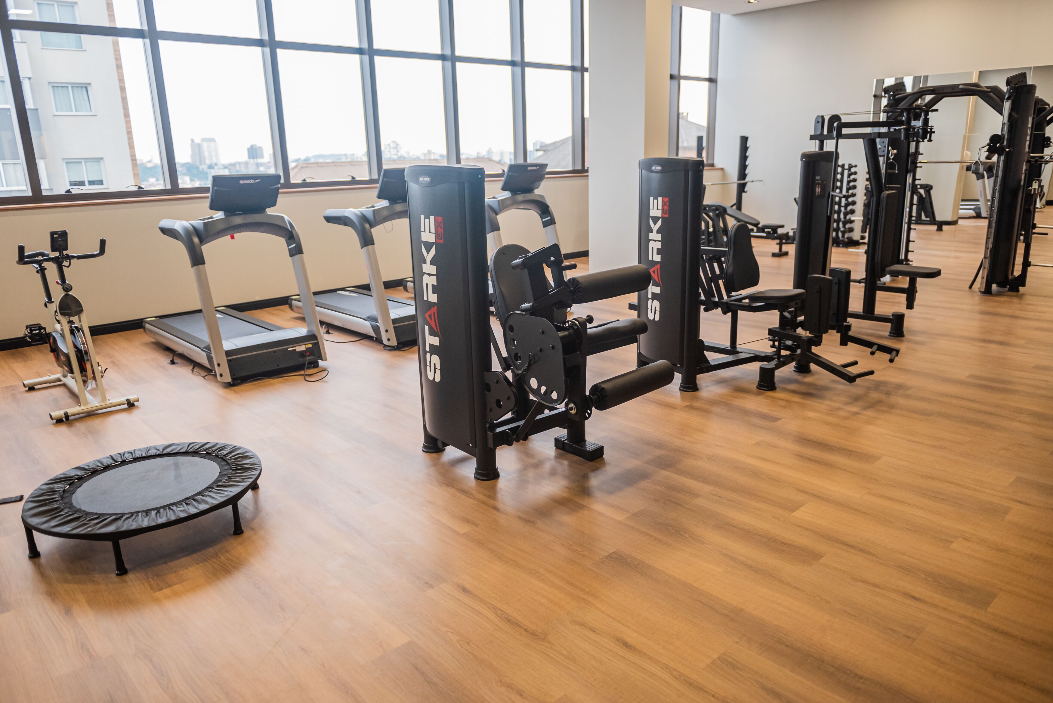 A gym with treadmills, weight machines, and a trampoline.