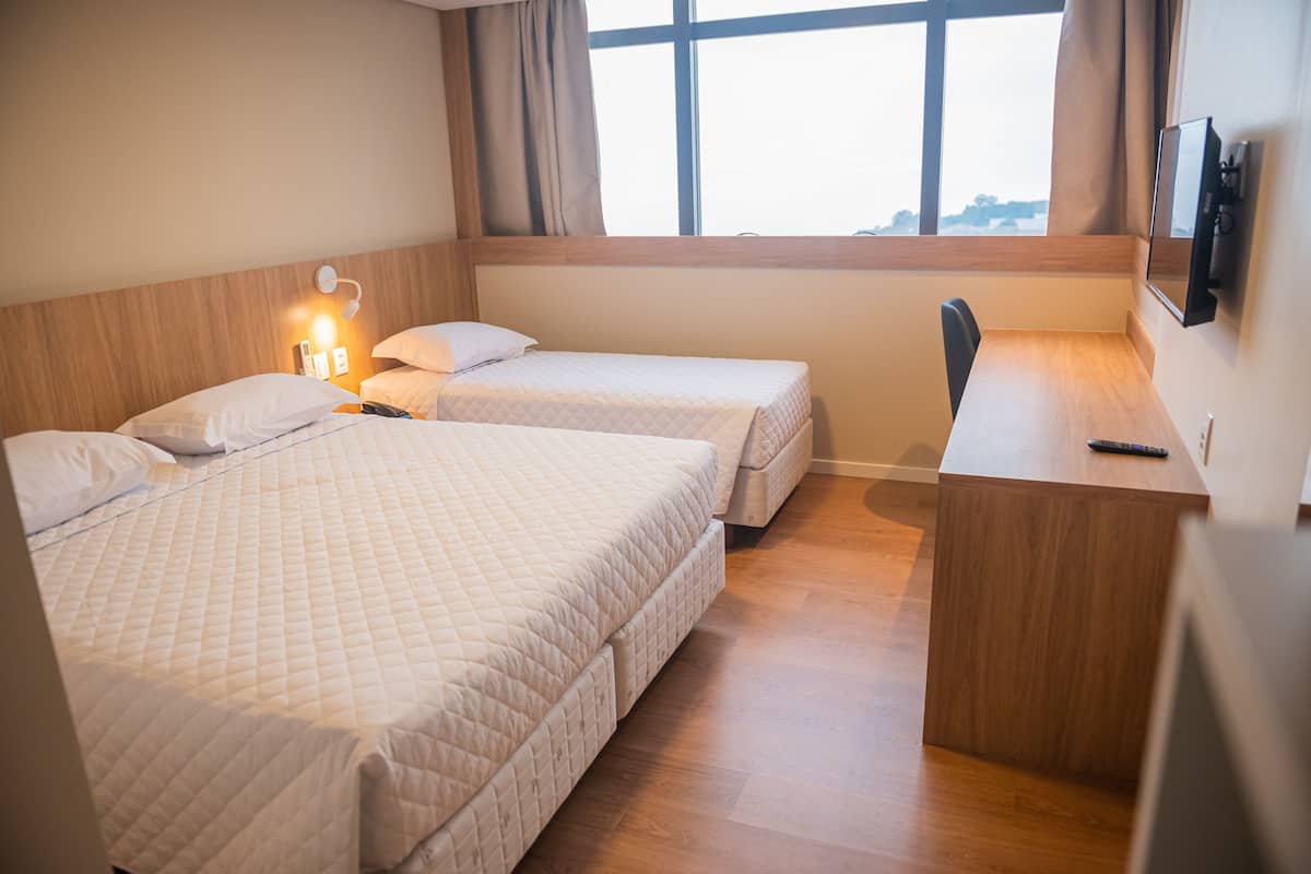 Una habitación de hotel con dos camas, un escritorio y un televisor.