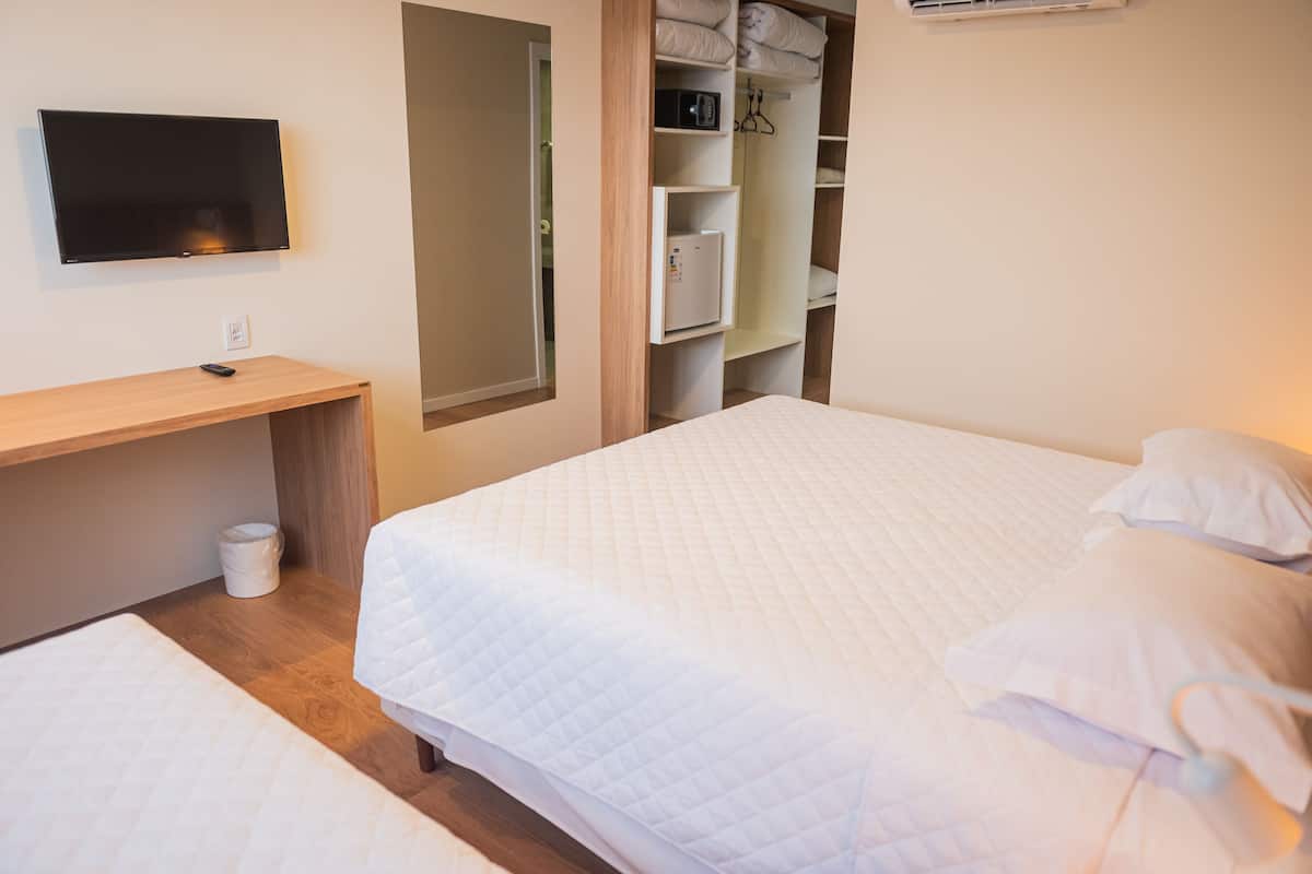 Un dormitorio con cama, escritorio, televisor y armario.