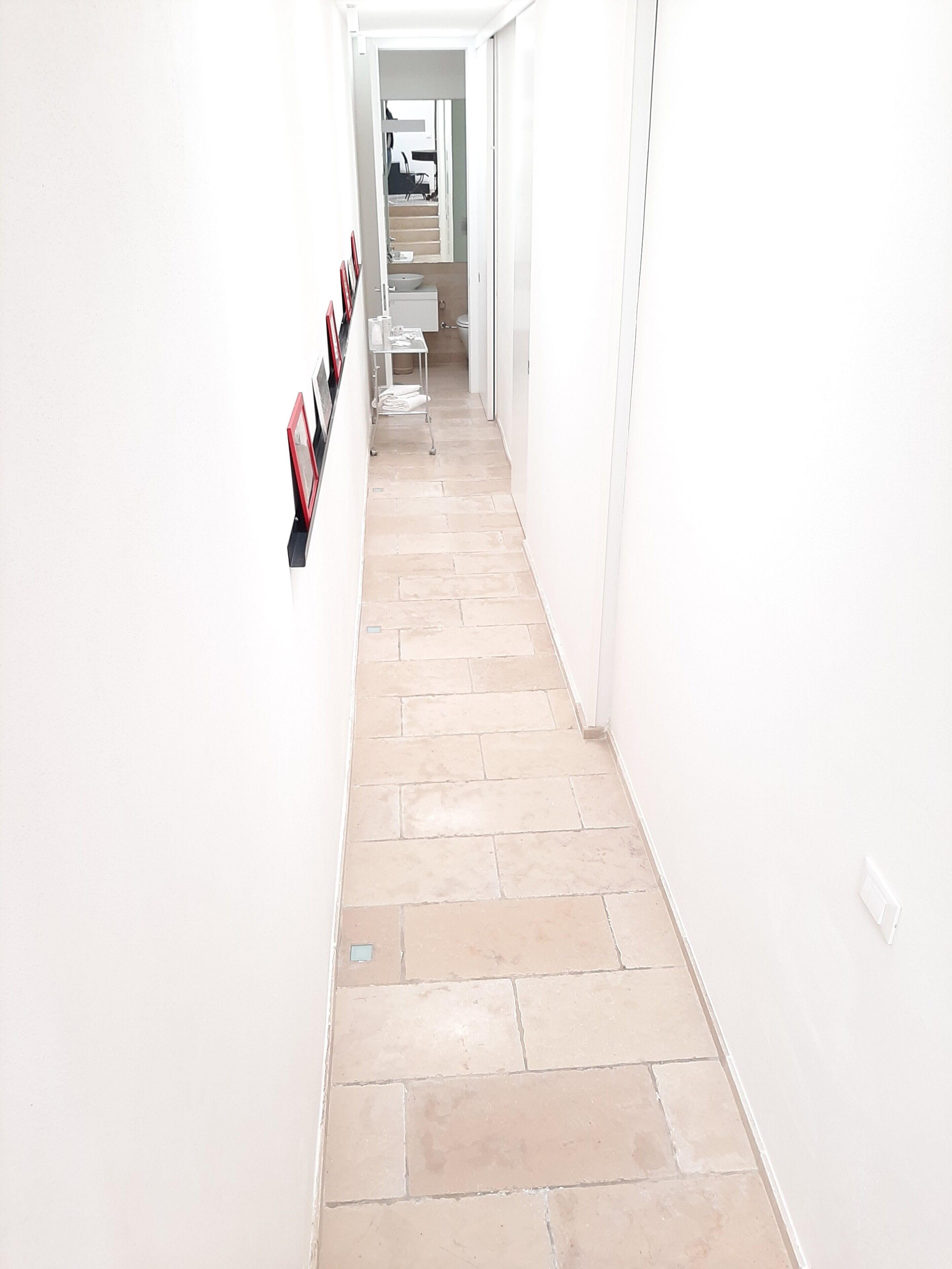 A narrow hallway with tiled flooring and white walls.