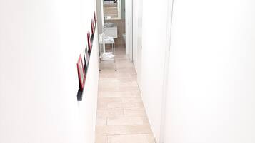 A narrow hallway with tiled flooring and white walls.