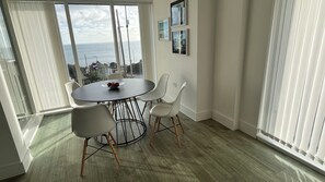 A dining area with a round table, four chairs, and a bowl of fruit.
