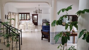 A spacious living area with a staircase, a dining area with white chairs, and a blue sofa. - Casa Rosa Montes (Lagos)