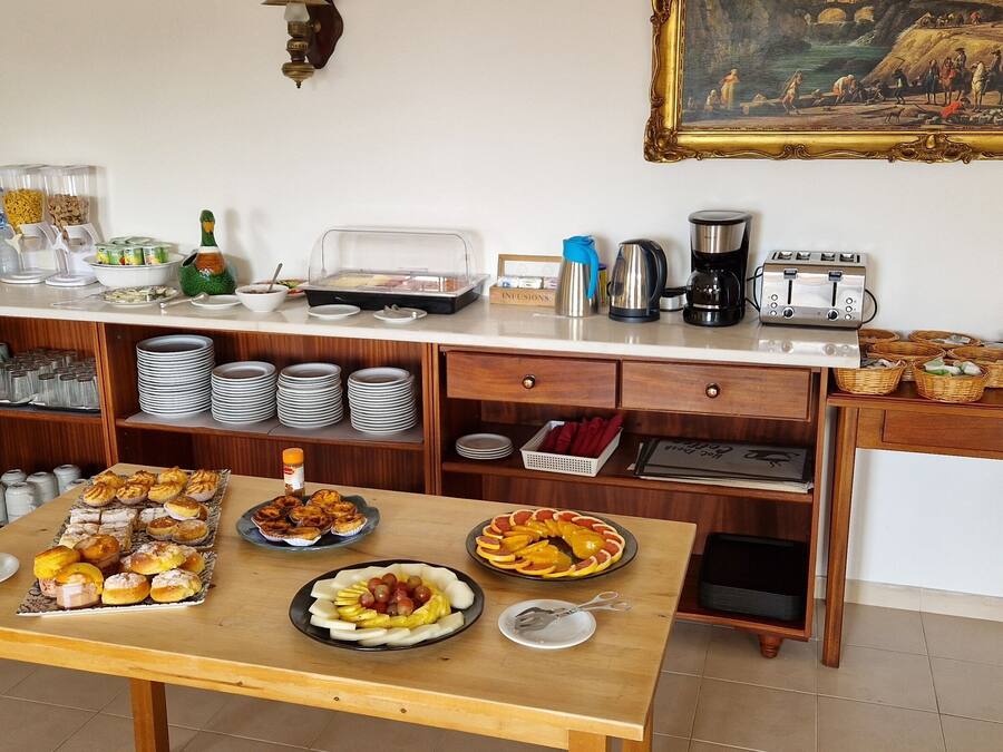 A breakfast buffet setup with various food items, a coffee machine, and a toaster.