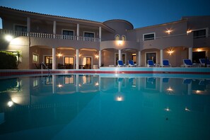A swimming pool with lounge chairs and a building with multiple balconies. - Casa Rosa Montes (Lagos)