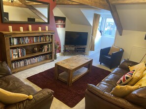 A cozy living room with a fireplace, bookshelves, a television, and leather sofas.