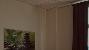 Une chambre d’hôtel avec un lit, un tableau au mur et une fenêtre avec des rideaux.