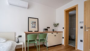 A small, modern room with a bed, a desk with two chairs, a coffee maker, and a framed picture on the wall. - HIŠANAVOGALU (AP.3)Cozy studio in Lesce, near Bled (Radovljica)