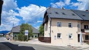 A street view with a two-story building with a sloped roof, a signboard, and a clear sky. - HIŠANAVOGALU (AP.3)Cozy studio in Lesce, near Bled (Radovljica)