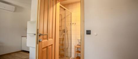 Puerta de madera que da a un baño con ducha e inodoro.