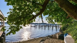 A lakeside view with a dock extending into the water, a covered seating area, and a kayak. - Pier on Main (Tiverton)