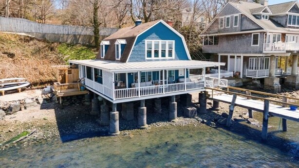 A waterfront house with a balcony, wooden deck, and a dock extending into the water. - Pier on Main (Tiverton)