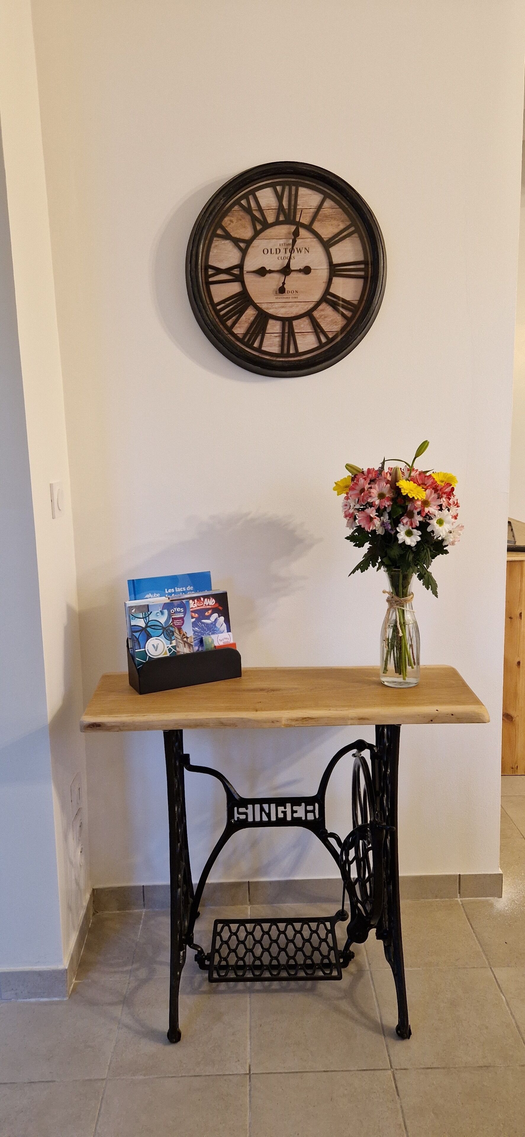 Ein Holztisch mit einer Uhr und einer Blumenvase darauf.