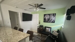 A compact living space with a kitchen area, dining table, and seating area. - 7 mins to the beach (Delray Beach)