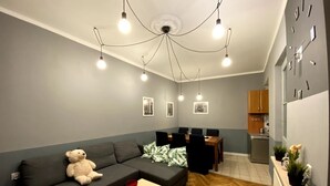A modern living room with a sofa, a dining table, and a kitchen area in the background. - Lares and Penates in Old Krakow,winter garden-5 min from the Rynok  Rynok Square (Kraków)