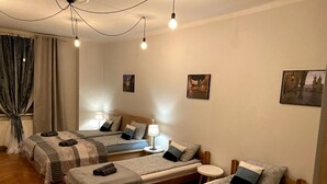 A hotel room with three beds, a wooden floor, and wall-mounted pictures. - Lares and Penates in Old Krakow,winter garden-5 min from the Rynok  Rynok Square (Kraków)