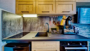 A modern kitchen with wooden cabinets, a stainless steel sink, and a built-in oven. - Apollo - au coeur du Corbier (Villarembert)