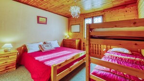 A cozy cabin-style bedroom with two bunk beds, wooden walls, a wooden ceiling, and a single bed with a red blanket. - Chalet les Colchiques (Fontcouverte-la-Toussuire)