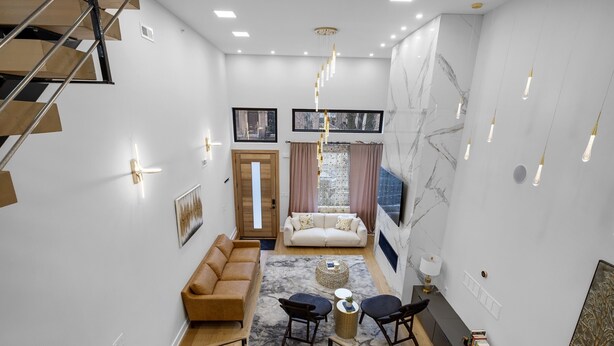 Un salon moderne avec un escalier, un canapé, une table basse et une bibliothèque.