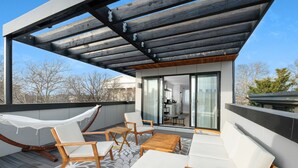 Une terrasse extérieure moderne, dotée d’un hamac, de chaises en bois et d’un canapé.